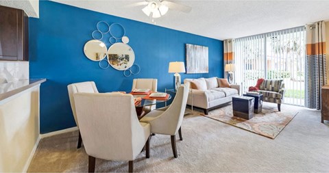 Living room and dining room area with plush carpeting and ample natural light in your home at Midora at Woodmont in Tamarac, FL